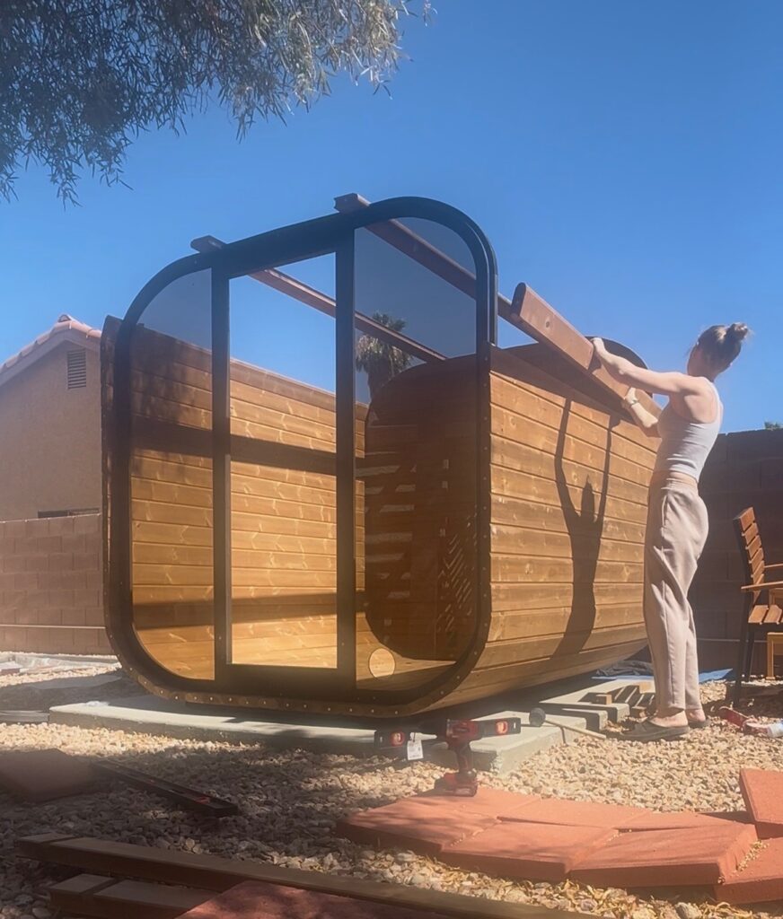 Emily fitting wooden boards along the curved top of the backyard sauna during construction.