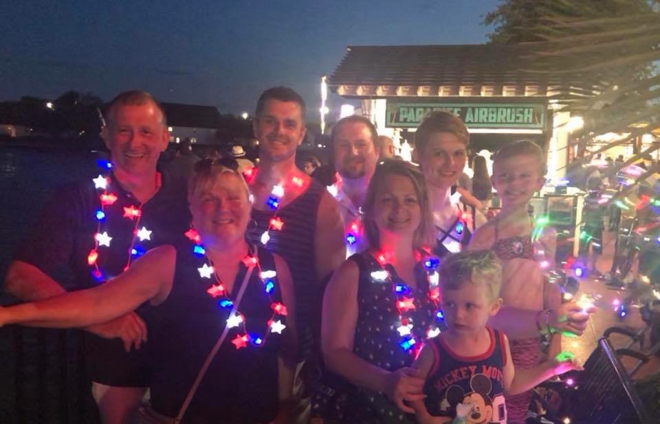 A group poses outdoors at night wearing glowing red and blue necklaces.