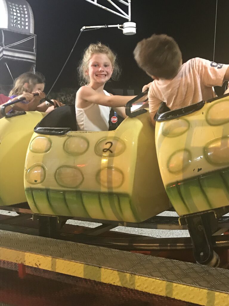 Children sit in a yellow caterpillar-shaped amusement ride.
